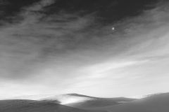 Palouse hills covered in light now, the moon floating by - black and white