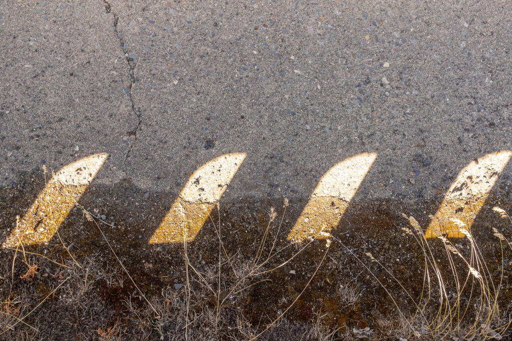 Photograph;
the old main street bridge with sunlight pattern on roadway from bridge side rails