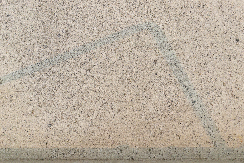 Photograph; sidewalk at the bottom of the stairs, yellow light from a smoke filtered sun and the  stair railing’s faint shadow.