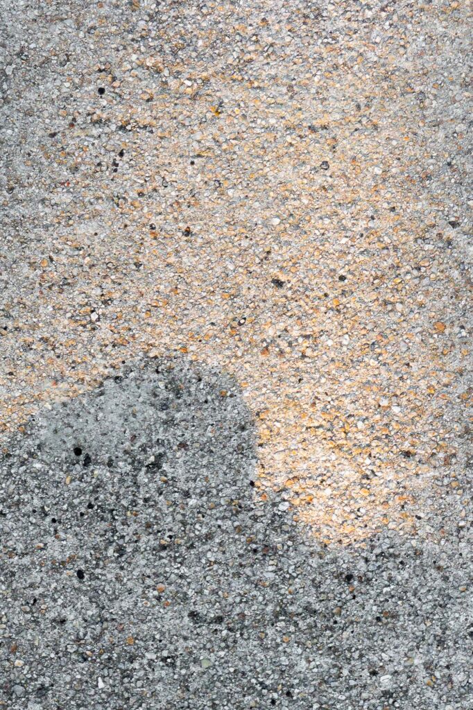 Photograph; The shadow of a rock outlined by the light of the morning sun on a sidewalk.