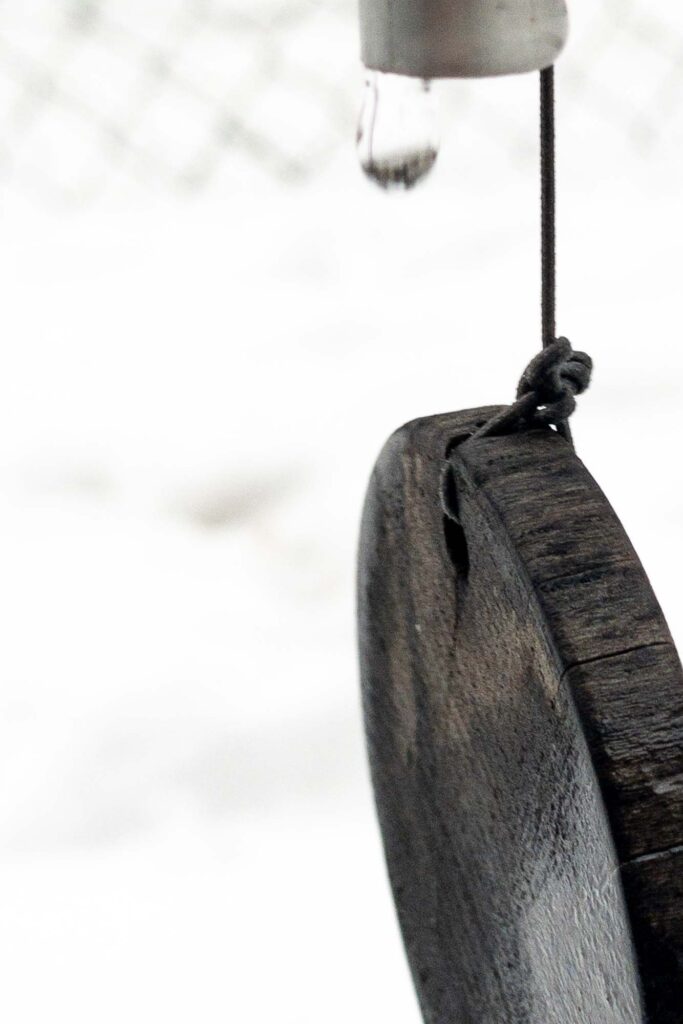 Photographs; A drop of water from melting snow, dripping off the tip of a chime in a wind, chime, the weight is a string tied to a weathered slice of wood.