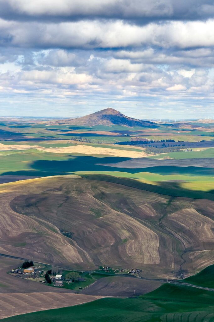 Color photograph of Steptoe Butte and the Palouse littered with shadows from passing clouds in early spring.