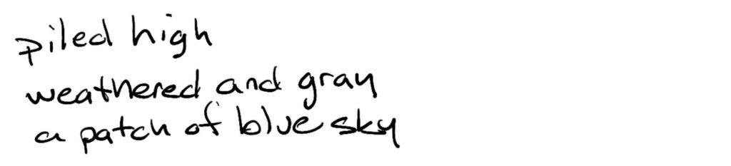 piled high/weathered and grey/a patch of blue sky