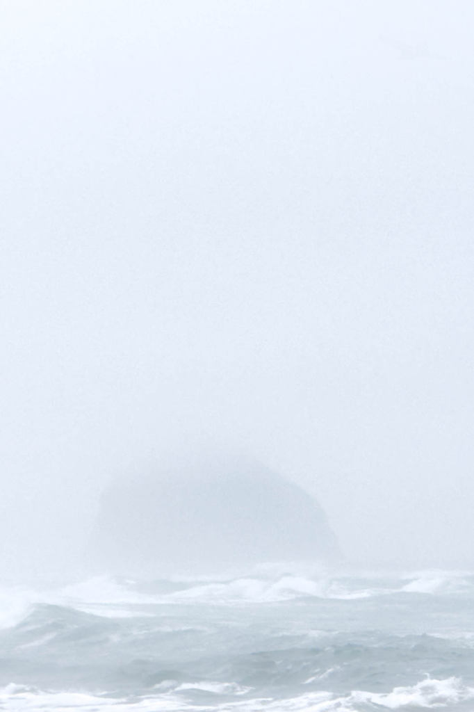 Haystack rock and wind blown ocean waves in the fog